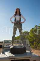 Full length of woman standing on off road vehicle with tire