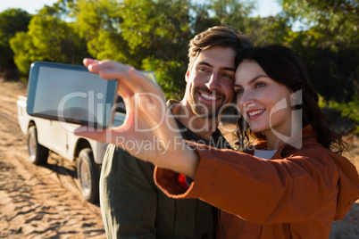 Young woman with man taking selfie on field