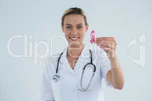 Portrait of female doctor showing Breast Cancer Awareness ribbon