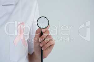 Female doctor with  Breast Cancer Awareness ribbon holding stethoscope