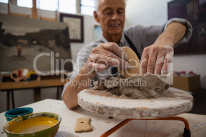 Attentive senior man molding clay