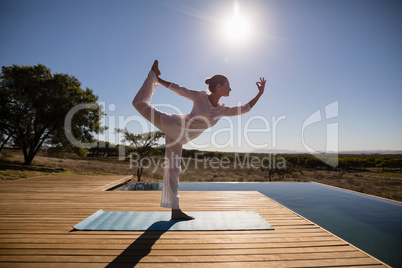 Woman practicing yoga on at poolside