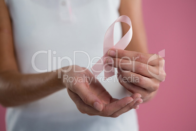 Mid section of young woman holding Breast Cancer Awareness ribbon