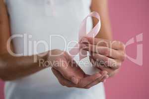 Mid section of young woman holding Breast Cancer Awareness ribbon