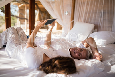 Happy couple using digital tablet on bed