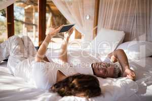 Happy couple using digital tablet on bed