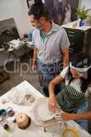 Man assisting woman in pottery