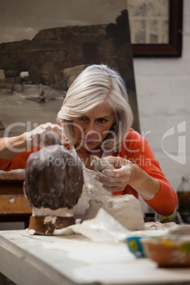 Attentive senior woman making a clay sculpture