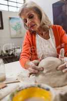 Attentive senior woman molding clay