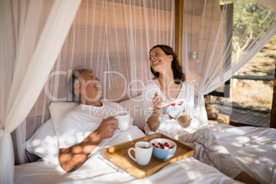 Happy couple having breakfast in canopy bed
