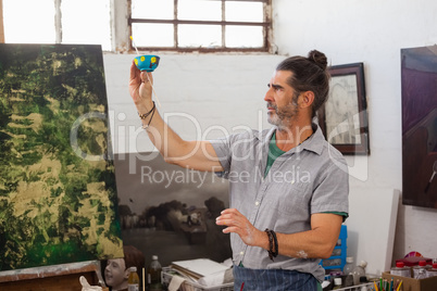 Attentive man looking at painted bowl