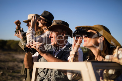 Friends looking through binoculars during safari vacation