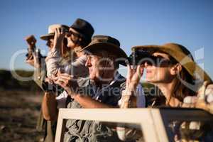 Friends looking through binoculars during safari vacation