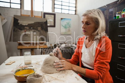 Mid-section of senior woman shaping a clay