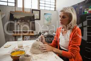 Mid-section of senior woman shaping a clay