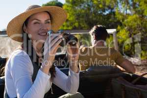 Woman using binocular with man driving off road vehicle at forest