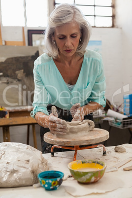 Attentive senior woman molding clay