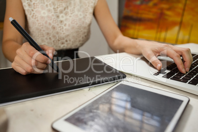 Woman using graphic tablet and laptop in drawing class