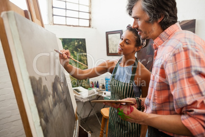 Man assisting woman in painting