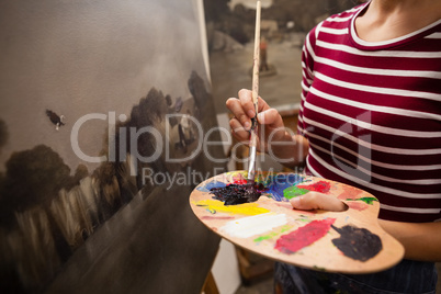 Woman painting on canvas in drawing class