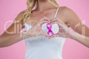 Breast Cancer Awareness ribbon seen through heart shape made by woman