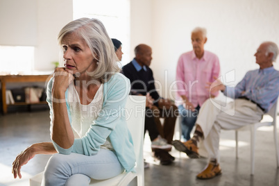 Worried senior female with friends in background