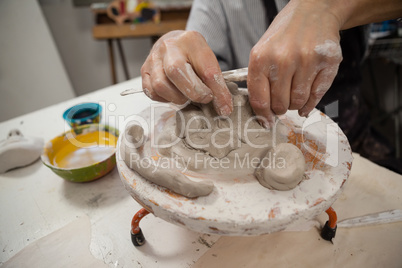 Mid section of man molding clay