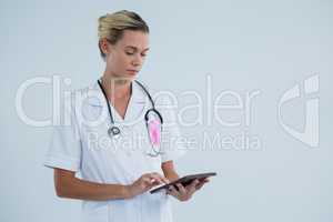 Female doctor with Breast Cancer Awareness ribbon using tablet computer