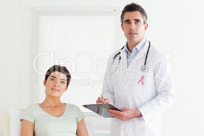 Doctor man with breast cancer awareness ribbon and patient