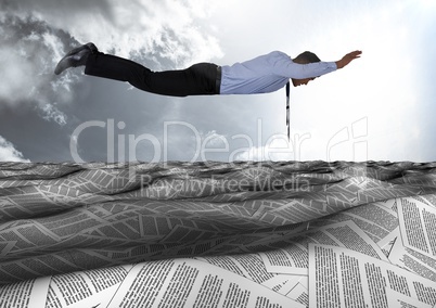 Businessman flying over sea of documents under sky clouds