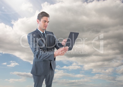 Businessman on tablet in front of sky