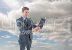 Businessman on tablet in front of sky