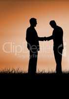 Business people shaking hands silhouette against sunset or sunrise