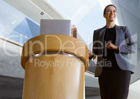 Businesswoman on podium speaking at conference with architectural perspective background