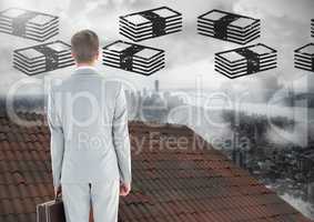 Money icons and Businessman standing on Roof with chimney and misty city