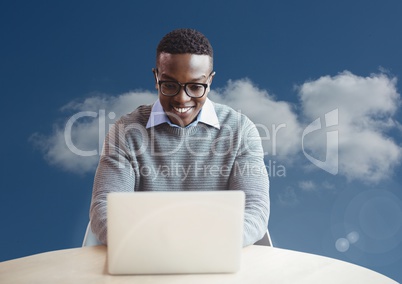 Man on laptop on desk in front of blue sky cloud