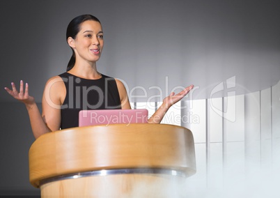 Businesswoman on podium speaking at conference with windows