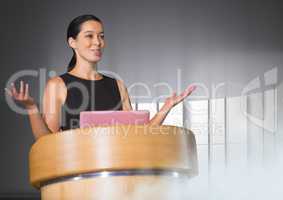 Businesswoman on podium speaking at conference with windows