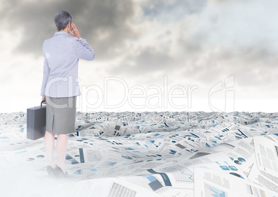 Businesswoman in sea of documents under sky clouds with briefcase