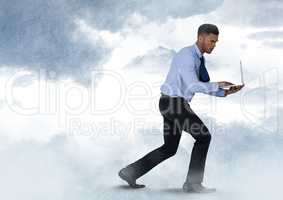 Businessman walking with laptop in cloudy sky