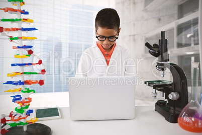 Composite image of schoolboy using laptop at desk