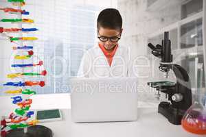 Composite image of schoolboy using laptop at desk