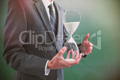 Composite image of mid section of businessman holding hourglass