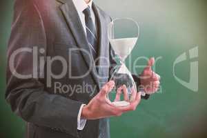 Composite image of mid section of businessman holding hourglass