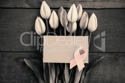 Overhead view of pink Breast Cancer Awareness ribbon with blank card on tulips