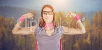 Composite image of portrait of smiling woman in superhero costume while flexing muscles