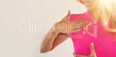 Mid section of woman with pink ribbon touching breast