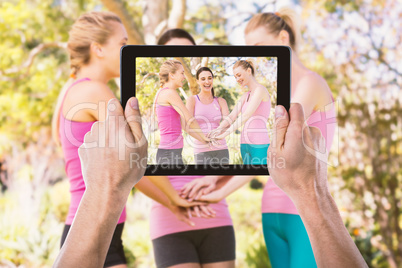 Composite image of cropped hand holding digital tablet