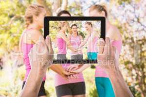 Composite image of cropped hand holding digital tablet