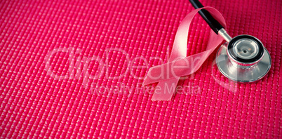 High angle view of stethoscope by pink Breast Cancer Awareness ribbon